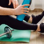 Mann trinkt nach dem Hanteltraining